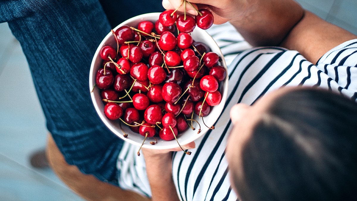 Woman holding bowl of cherries
