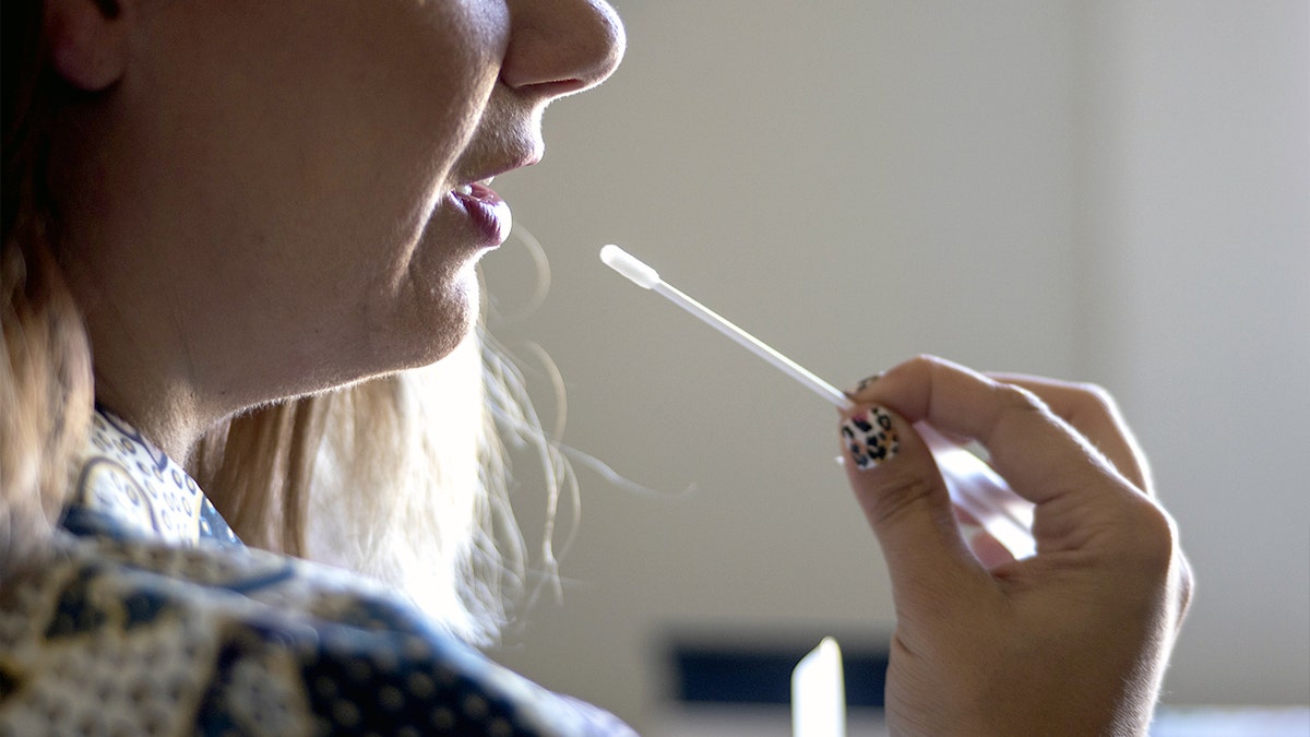 Uma mulher segura um cotonete de um kit de teste de DNA.