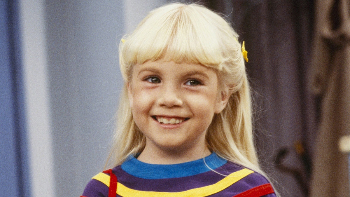 Heather O'Rourke smiling in a colorful sweater.