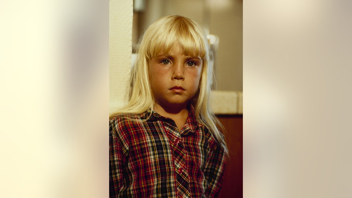 Heather O'Rourke looking serious in a plaid shirt.