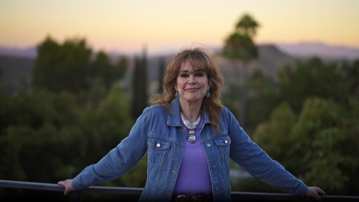 Holly Hallstrom posing in a denim jacket smiling against a California backdrop.