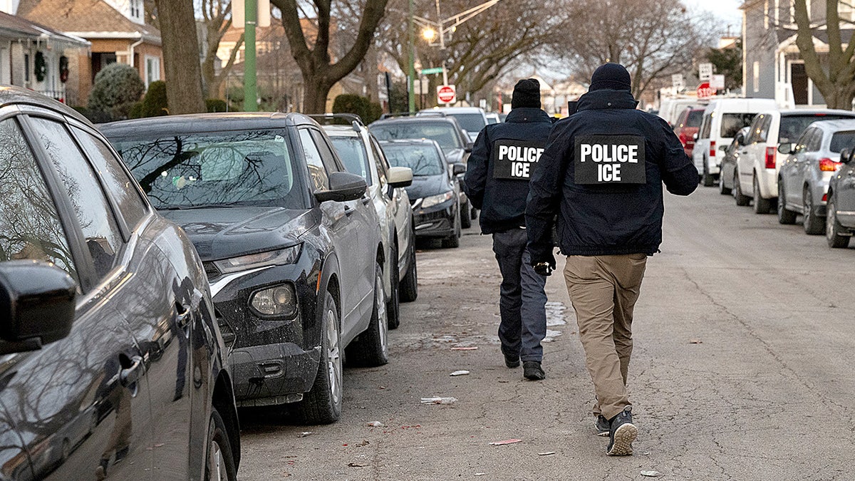 ICE agents walking down a city street during an enforcement operation.