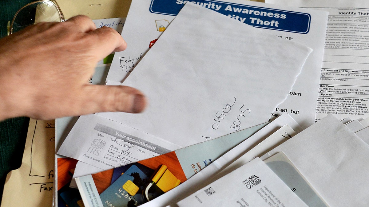 A hand reaches toward a spread of documents.
