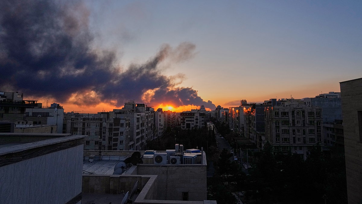 The sun setting behind a plume of smoke rising in Tehran, Iran.