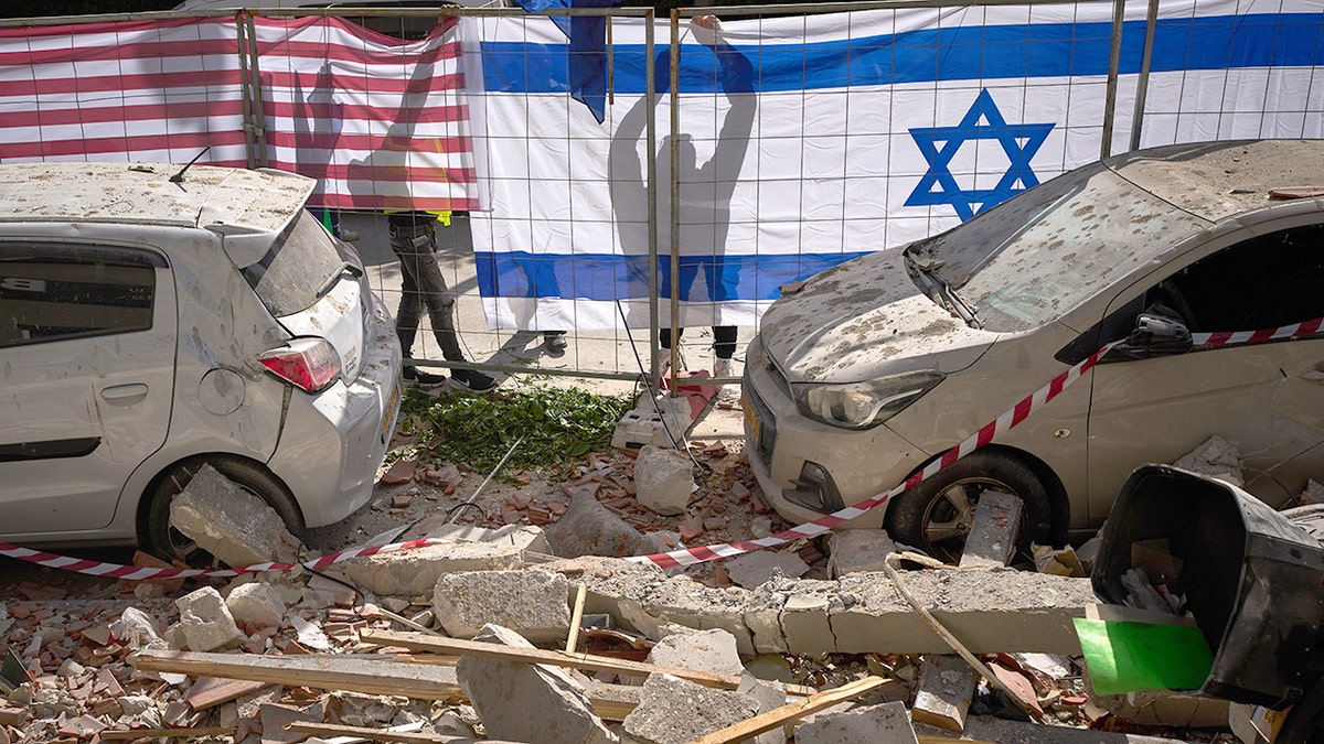 Israeli authorities hanging Israeli and U.S. flags at a missile strike site in Ramat Gan.