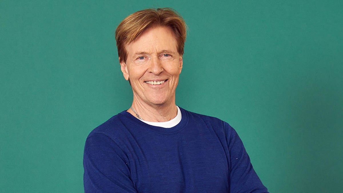 Jack Wagner smiling against green background
