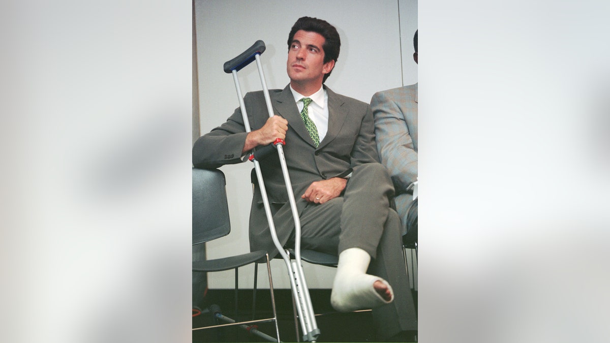 John F. Kennedy Jr. with an injured ankle holding onto his crutch.
