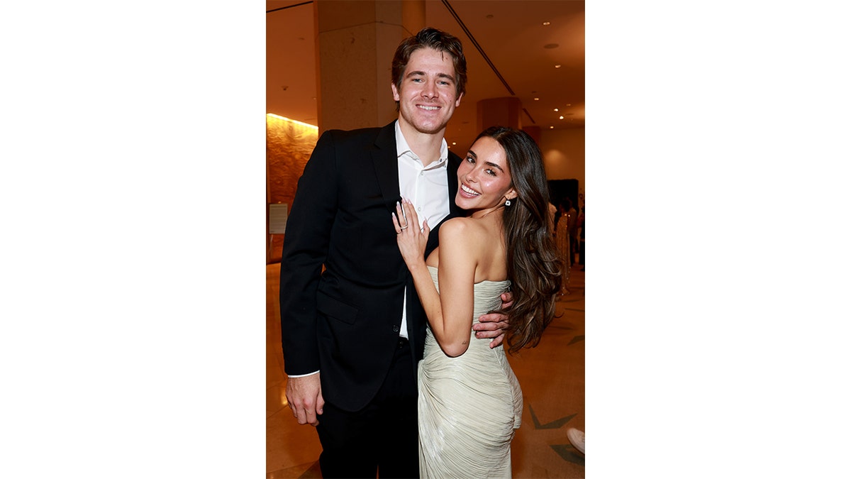 Justin Herbert and Madison Beer posing together at a formal indoor event.