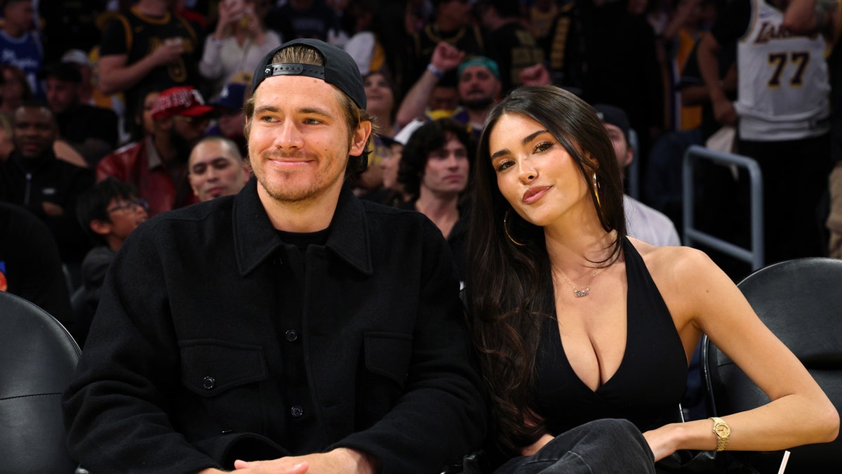 Justin Herbert and Madison Beer sitting courtside at a basketball game.