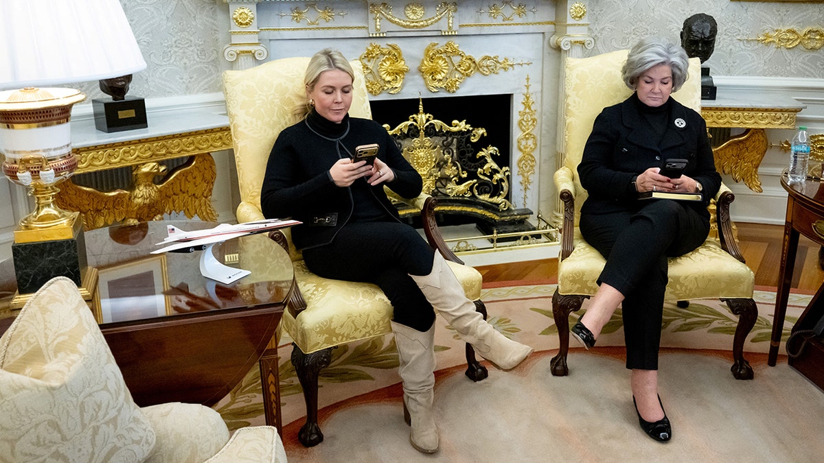 Karoline Leavitt and Susie Wiles look at their phones in the Oval Office