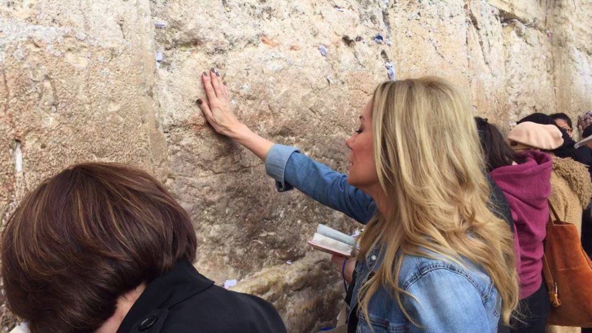 Kathie Lee Gifford placing her hand against a wall.