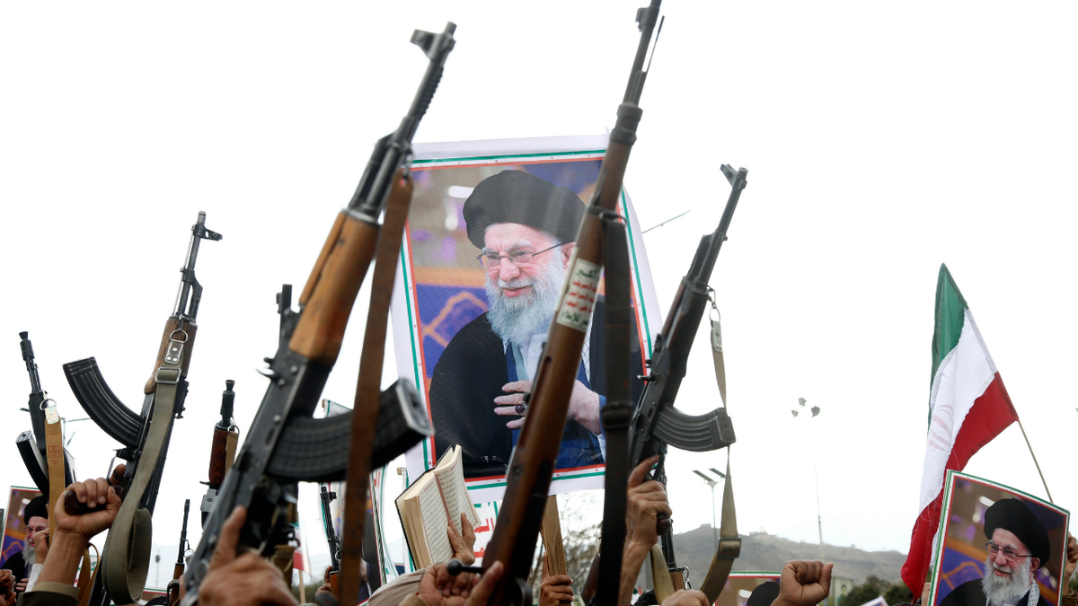 Pro Iran supporters holding weapons and displaying imagery of Ayatollah Khamenei at a rally