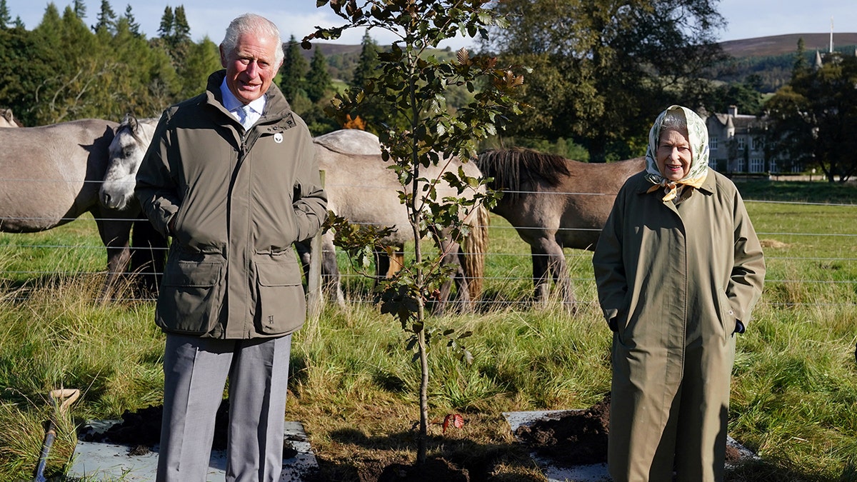 The former Prince Charles and Queen Elizabeth standing together outdoors at Balmoral.