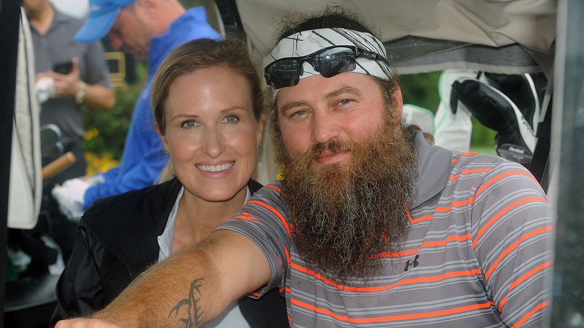Korie Robertson and Willie Robertson standing together at a golf event.