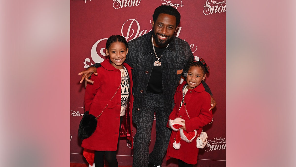 Kountry Wayne posing with his children at a film screening.
