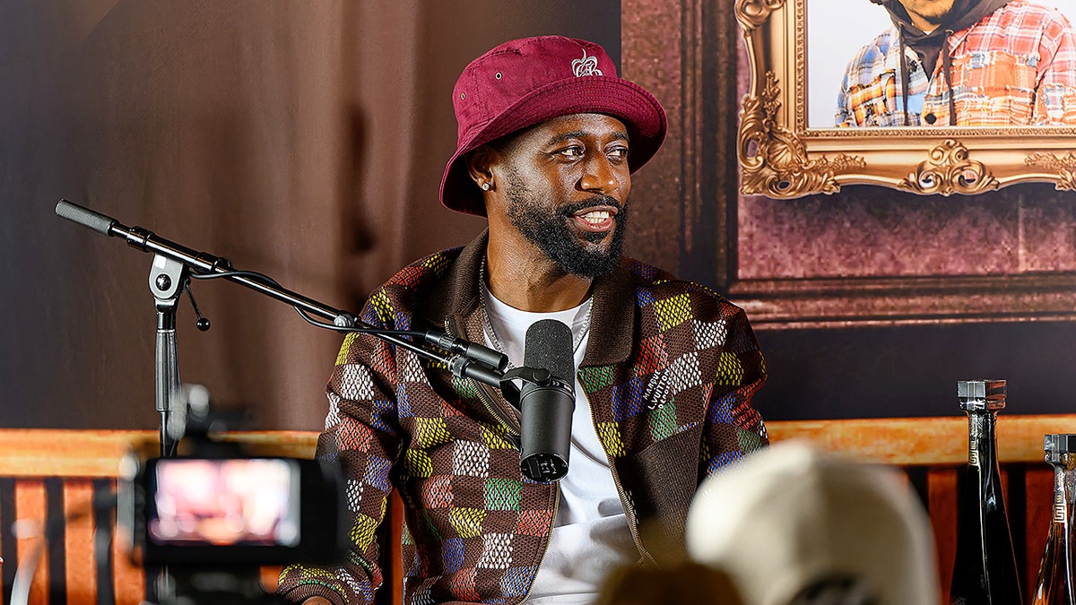 Kountry Wayne speaking into a microphone at an event.
