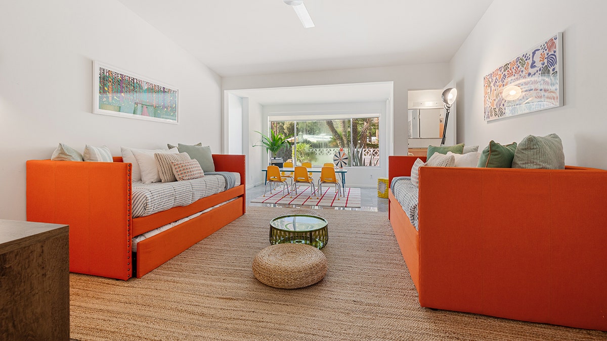 A second living area features orange couches and another dining room.