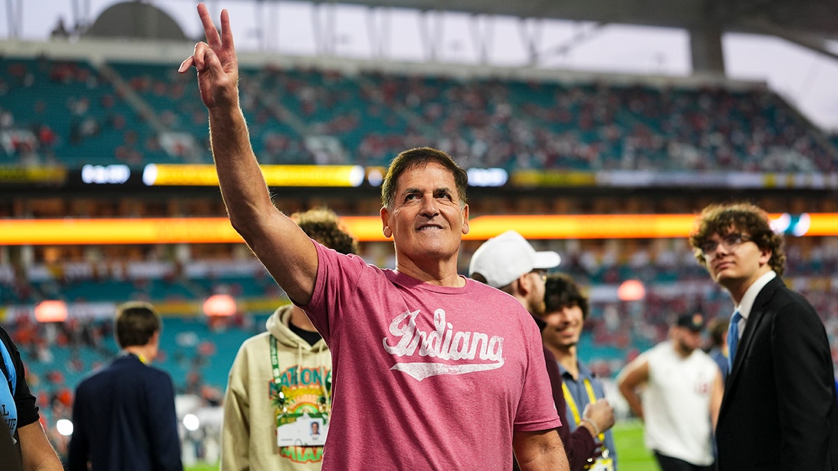 Mark Cuban waves to the crowd before the 2026 CFP National Championship between the Miami Hurricanes and the Indiana Hoosiers at Hard Rock Stadium on January 19, 2026 in Miami Gardens, Florida. Seen giving peace sign wave and wearing Indiana t-shirt looking up at stands.