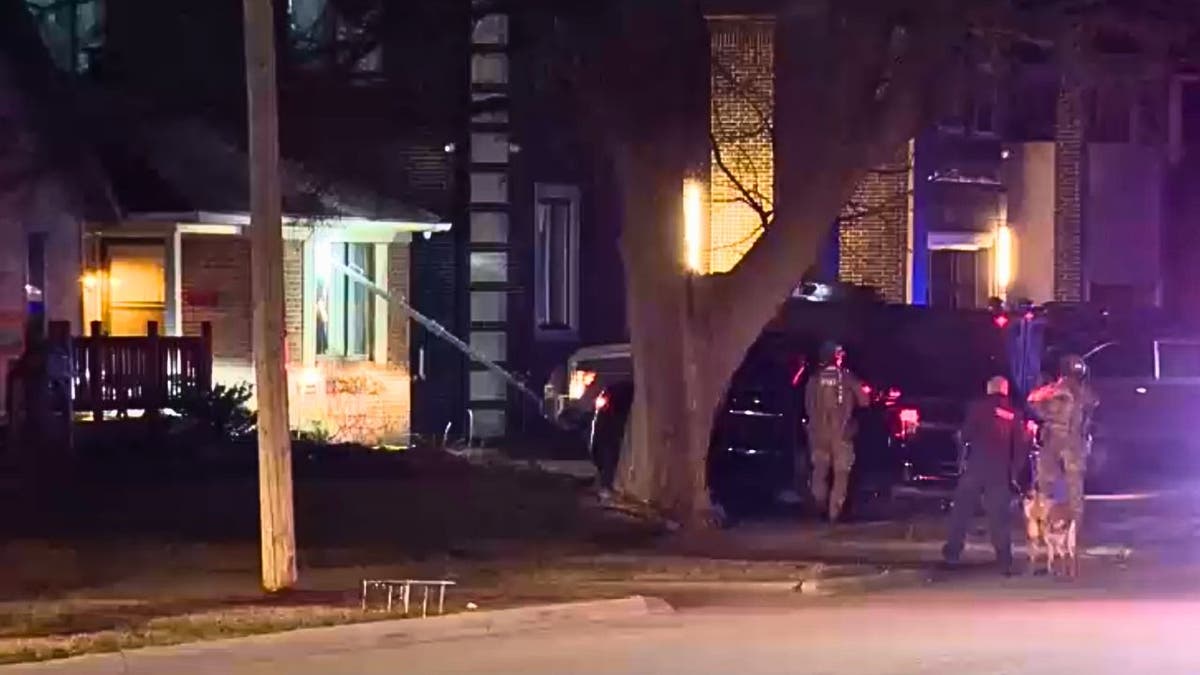 FBI agents in tactical gear break a front window while executing a search warrant at a home in Dearborn Heights, Michigan at night.