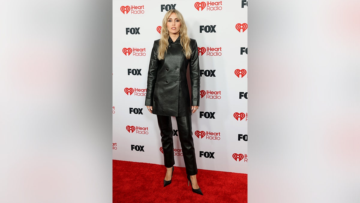 Miley Cyrus wore a long black jacket to the iHeartRadio Music Awards in 2026.
