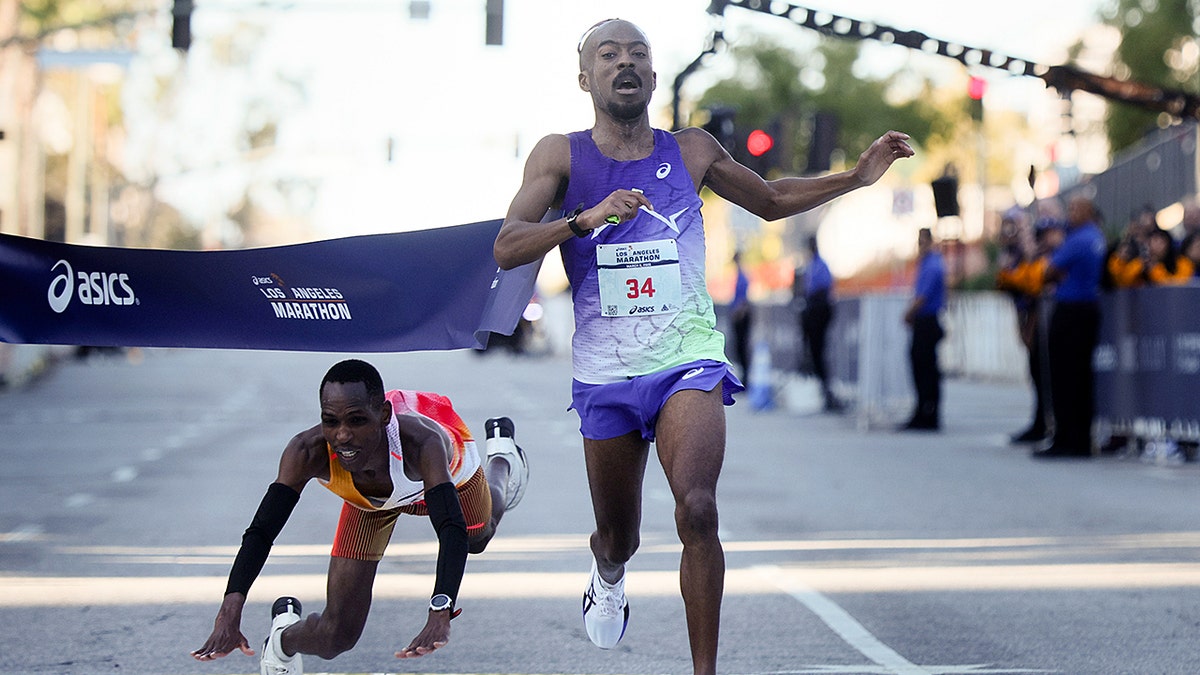 Nathan Martin crosses a marathon finish line while Michael Kimani Kamau falls to the pavement.