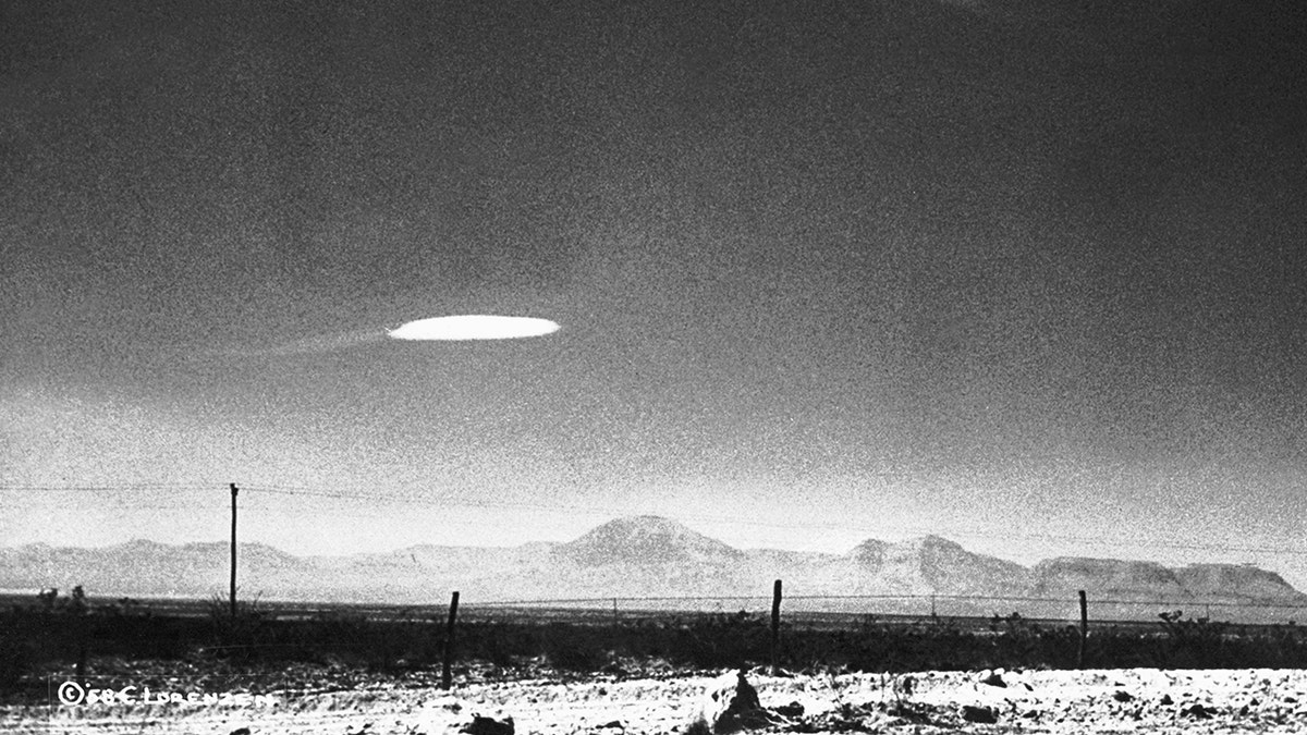 Uma foto em preto e branco de um OVNI pairando sobre uma paisagem no Novo México