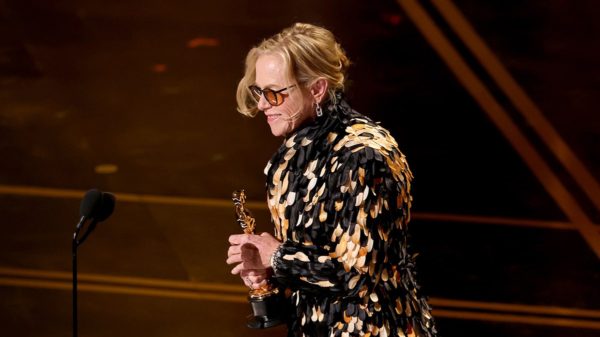 Amy Madigan accepts the best supporting actress award on stage at the Oscars.