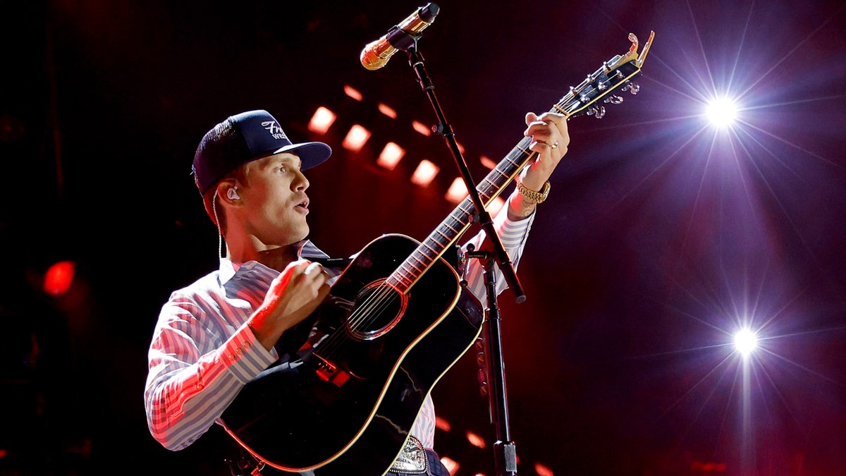 Parker McCollum performing on a stage inside a stadium.