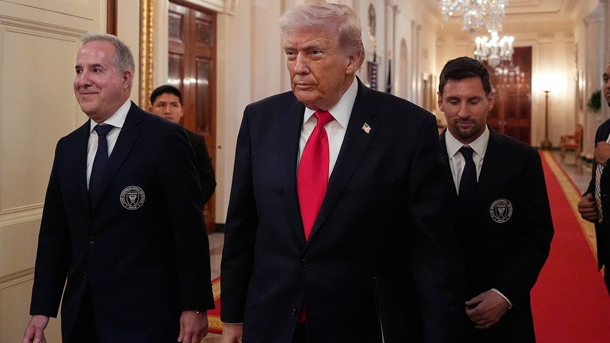 President Donald Trump walking into the East Room with Jorge Mas Santos and Lionel Messi.