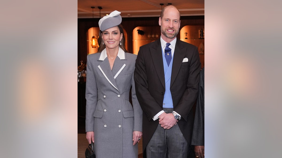 The Prince and Princess of Wales standing shoulder to shoulder smiling in formal wear.