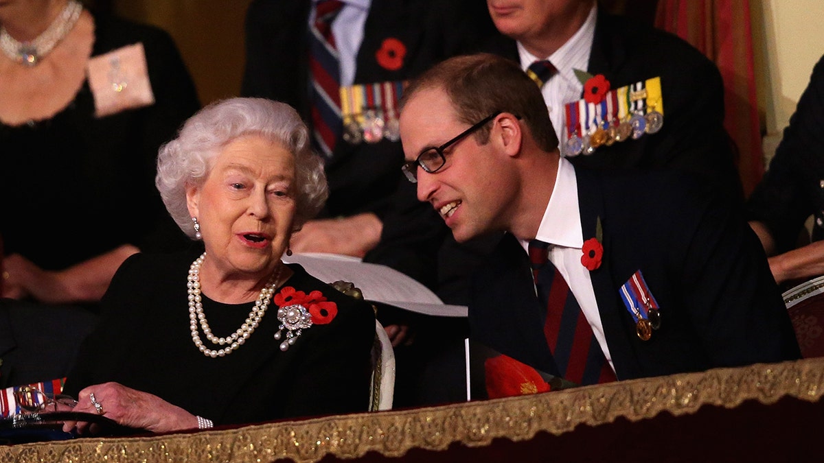 Queen Elizabeth II chatting with Prince William who is smiling and wearing glasses.