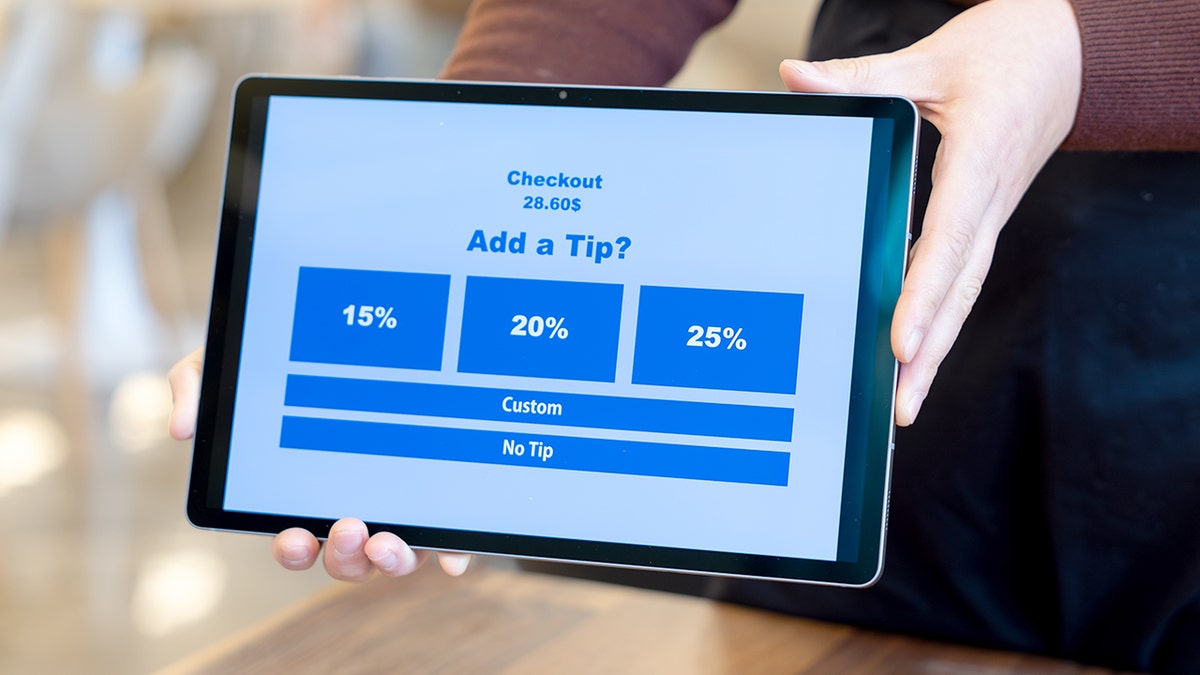 A tip screen shows 15%, 20% and 25%, with smaller options for "custom" and "no tip." It's being held.