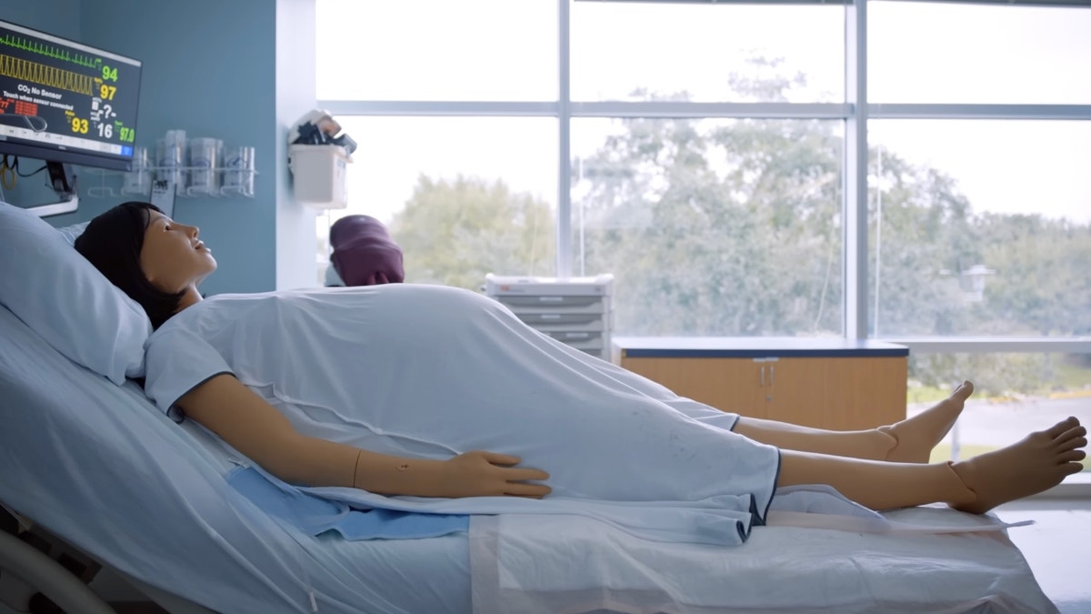Mama Anne is a high-fidelity childbirth simulator, and it is lying on a hospital bed.