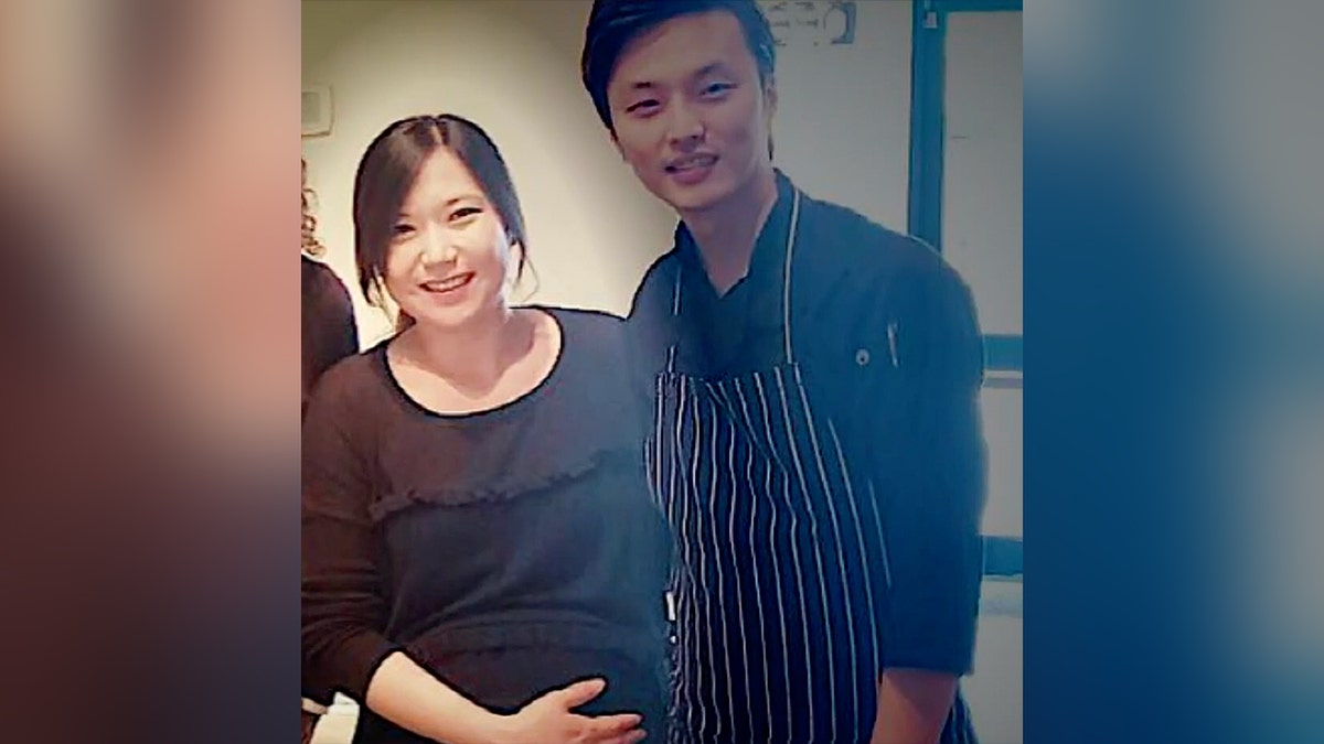 Eina Kwon holds her belly while smiling next to her husband