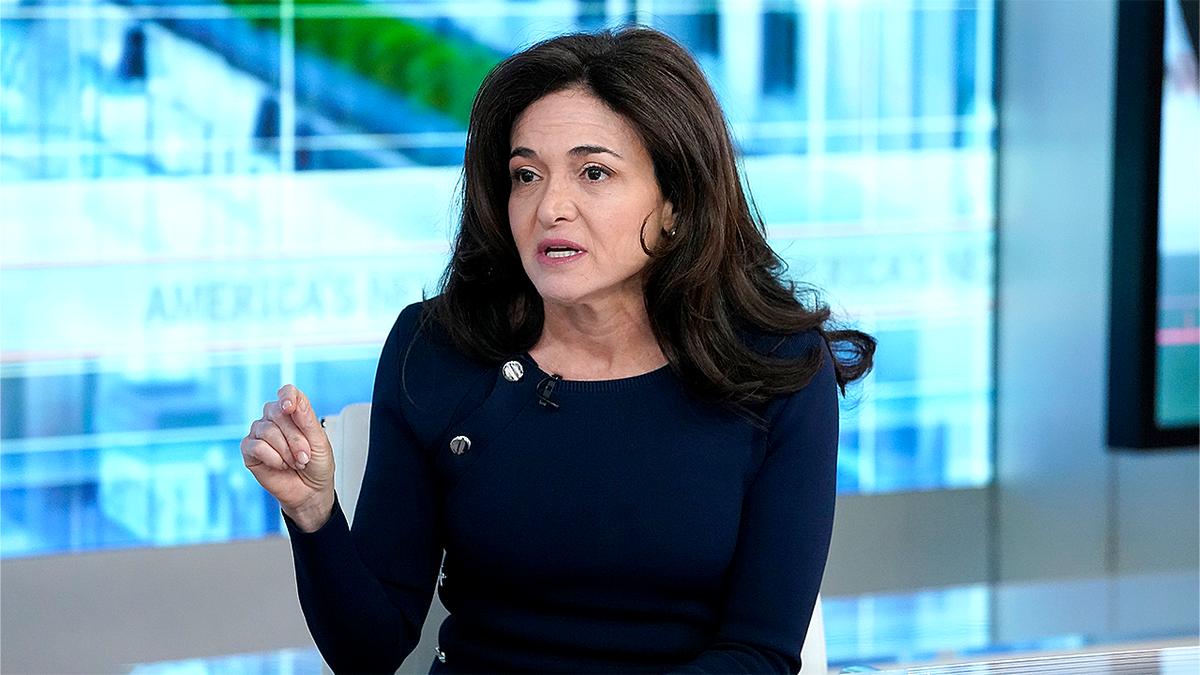 Sheryl Sandberg sitting and pointing finger