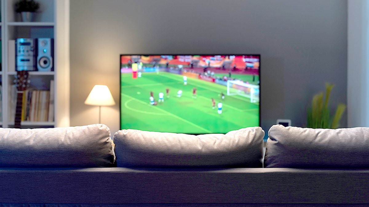A widescreen flat TV showing a football match in a living room