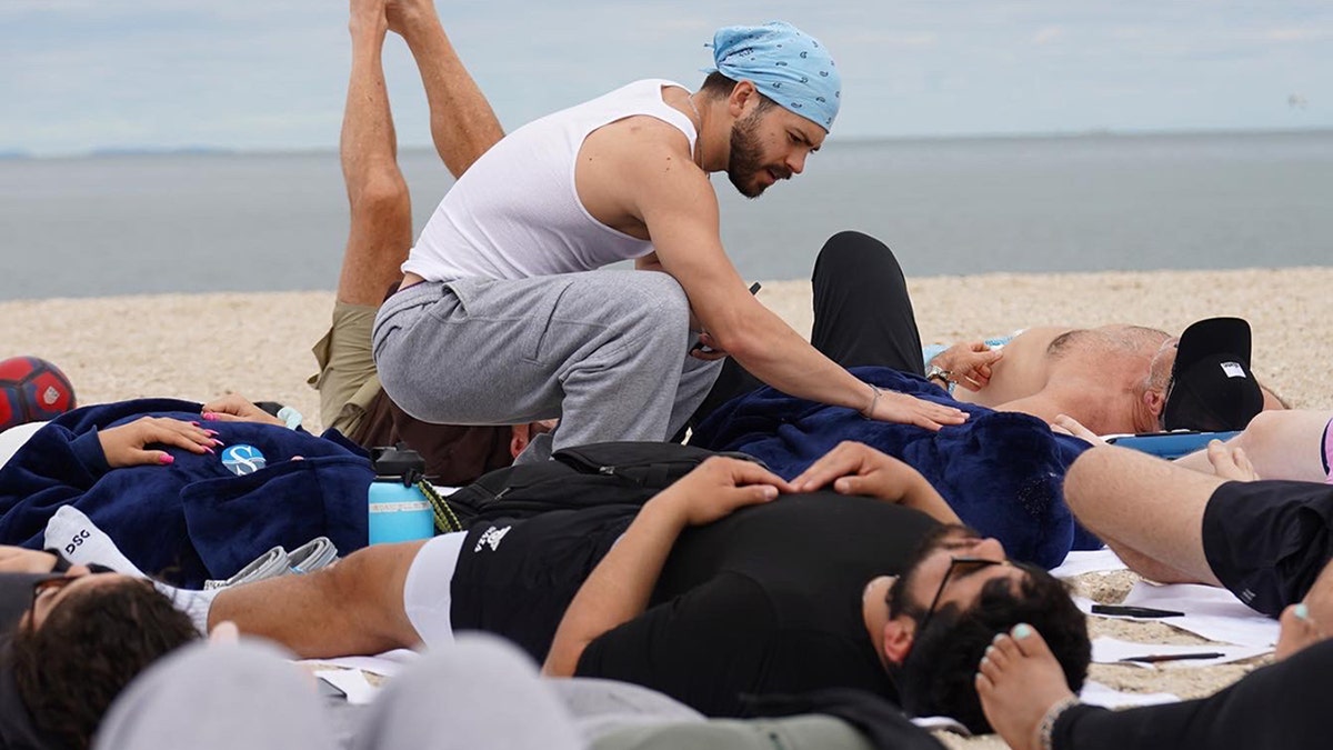 brendan cooke assists in breathwork on a beach