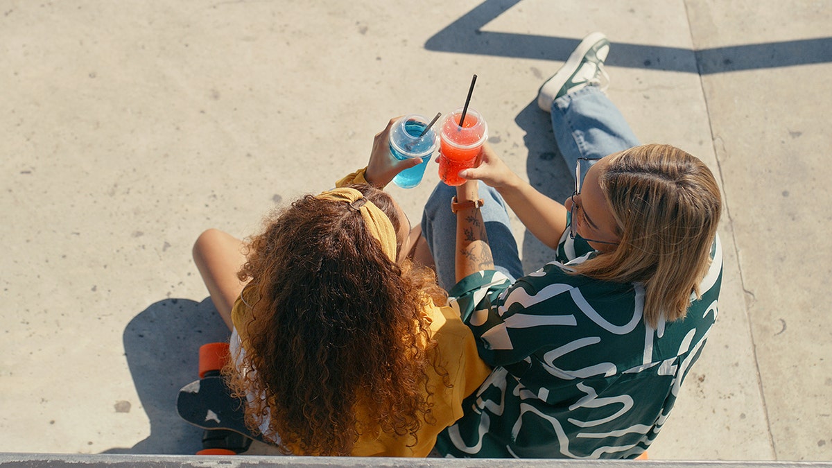 girls enjoy colorful drinks outside