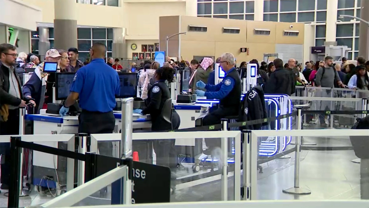 TSA agents screening passengers astatine  airdrome  information    checkpoint with travelers successful  enactment     and luggage scanners successful  a engaged  terminal.