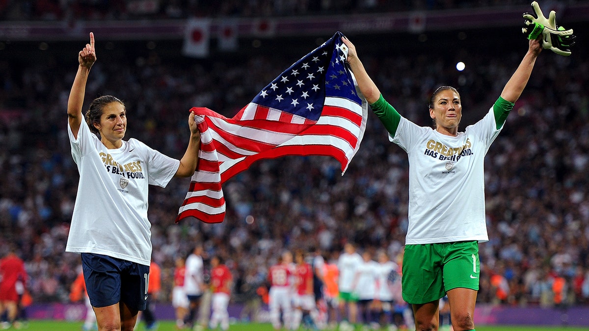 Hope Solo and Carli Lloyd celebrate with the American flag