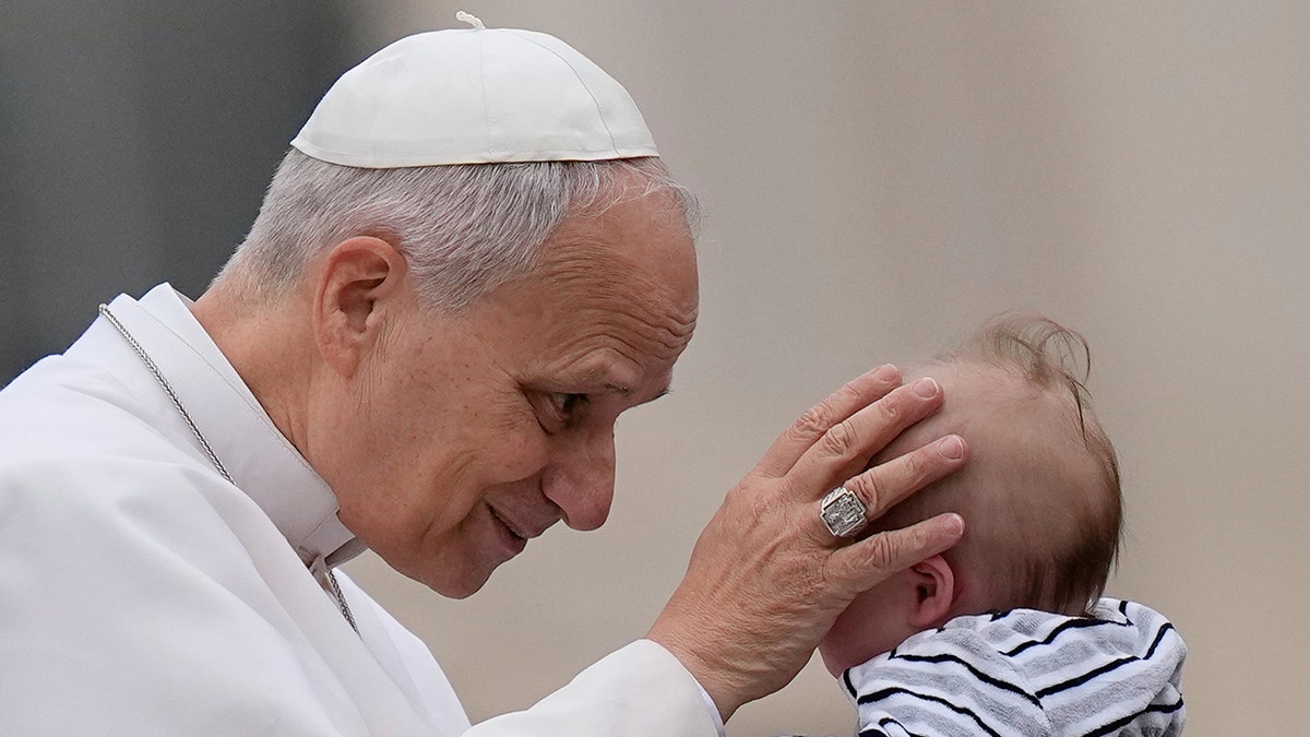 Pope Leo XIV blessing a child in St. Peter's Square.