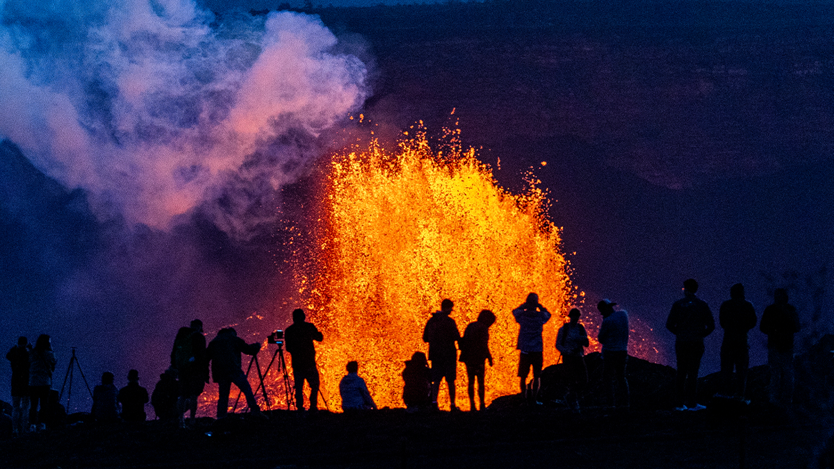 Hawaii's Kilauea Volcano erupts as people watch near by.