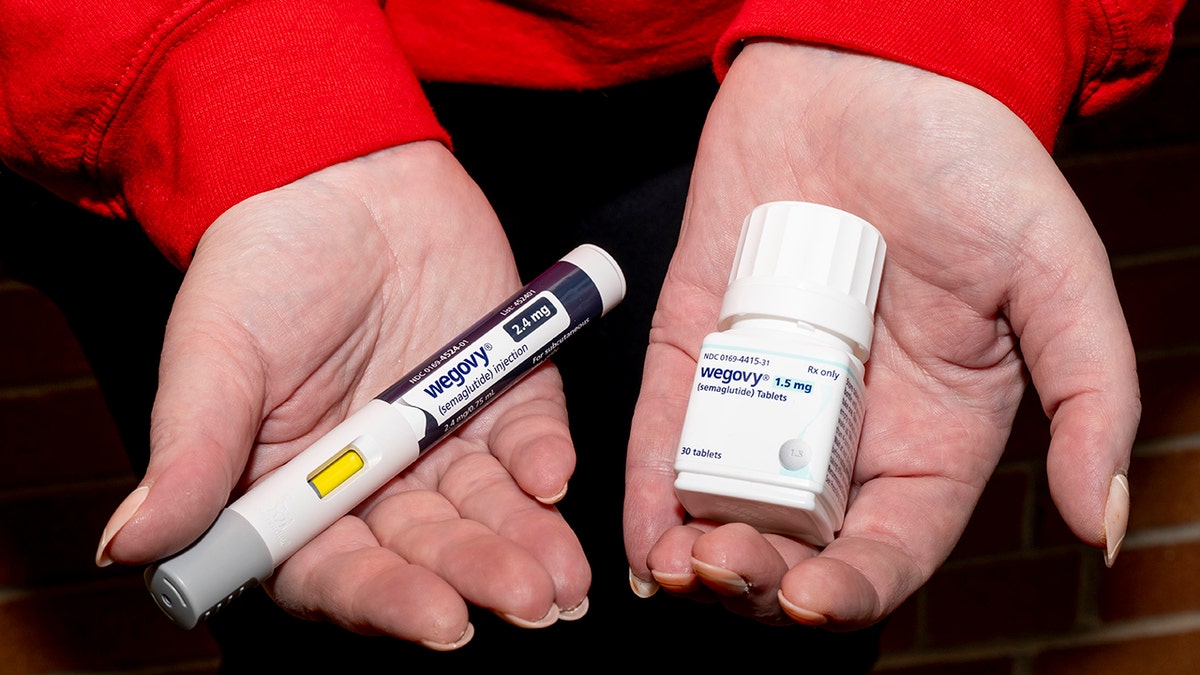 woman's hands holding wegovy injection in one and pill bottle in the other
