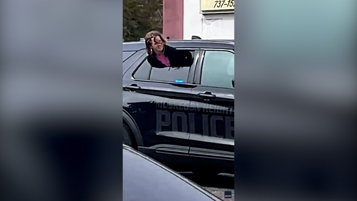 woman pokes her head outside of police car window