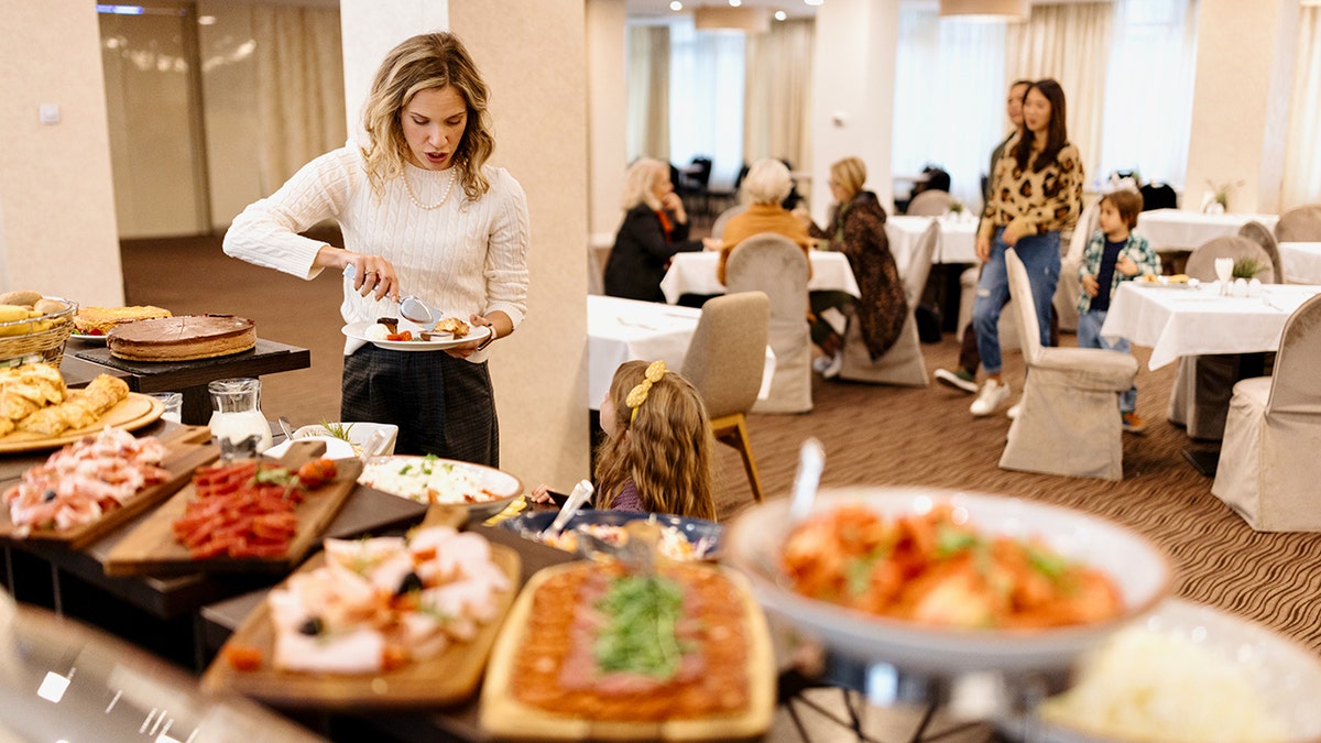 Woman preparing a plate of food from the hotel buffet table.
