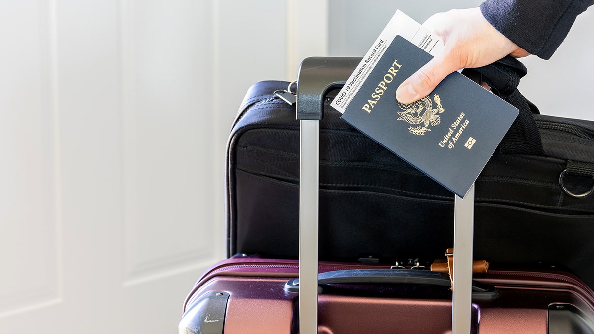 Close up   of a woman's manus  carrying a US passport and luggage.
