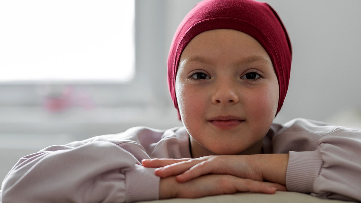 Young girl covering her head after being treated for cancer