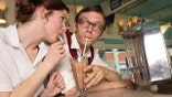 Retro couple sharing a milkshake in a diner booth