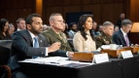 Top U.S. intelligence officials sit in a row as they testify before a Senate committee on global threats.