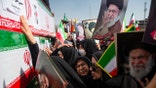Mourners reaching out to touch coffins while holding pictures of Ayatollah Ali Khamenei during a funeral in Isfahan.